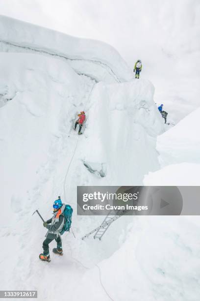 rope team navigating a big crevasse in the himalayas - khumbu stockfoto's en -beelden