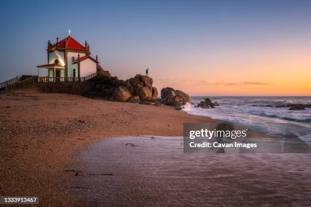 man on top of a rock with a light on the hand in a chapel by the beach - porto district portugal stock pictures, royalty-free photos & images