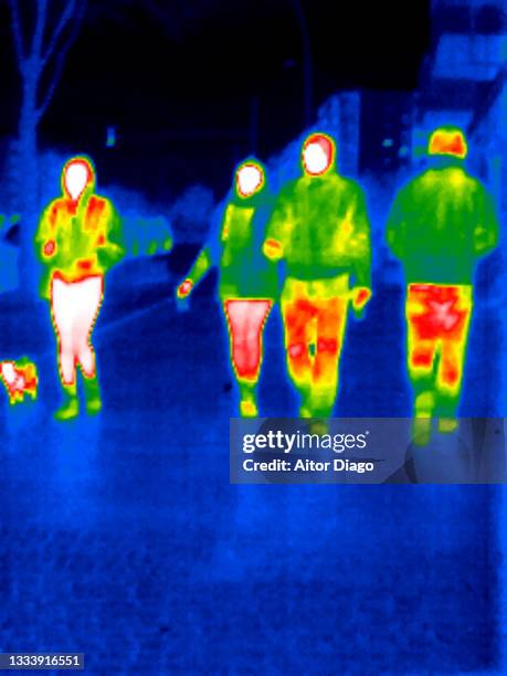 thermal image of unrecognizables persons  walking on the street. there is as well a small dog. - wärmebild stock-fotos und bilder