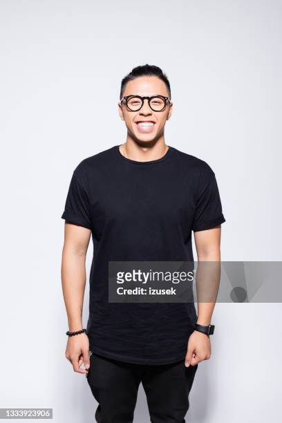fröhlicher asiatischer junger mann in schwarzer kleidung - t shirt stock-fotos und bilder