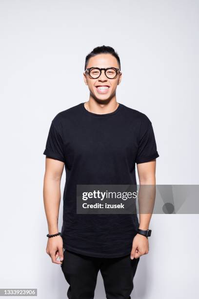 cheerful asian young man in black clothes - zwarte kleur stockfoto's en -beelden