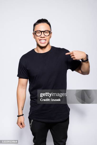 cheerful asian young man in black clothes - man pointing stock pictures, royalty-free photos & images