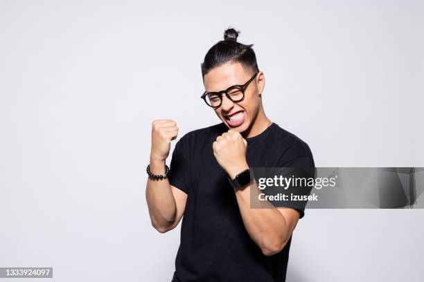 excited asian young man in black clothes - success stockfoto's en -beelden