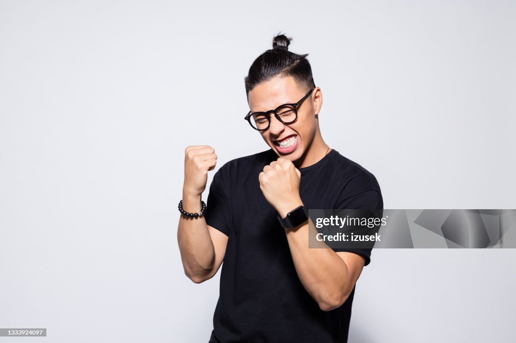 Excited asian young man in black clothes