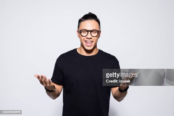 happy asian young man in black clothes - explaining stock pictures, royalty-free photos & images