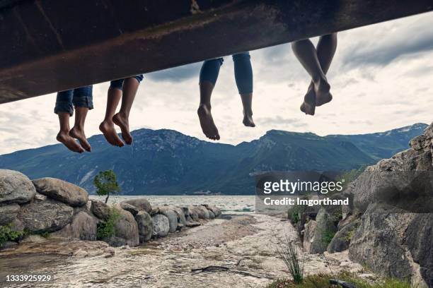feet of family sitting n a bridge in limone sul garda - teen boy barefoot 個照片及圖片檔
