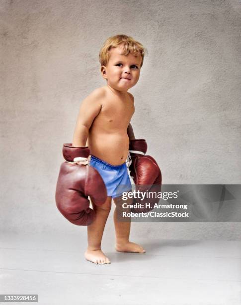 1930s Baby Boy Toddler Wearing Oversize Boxing Gloves .