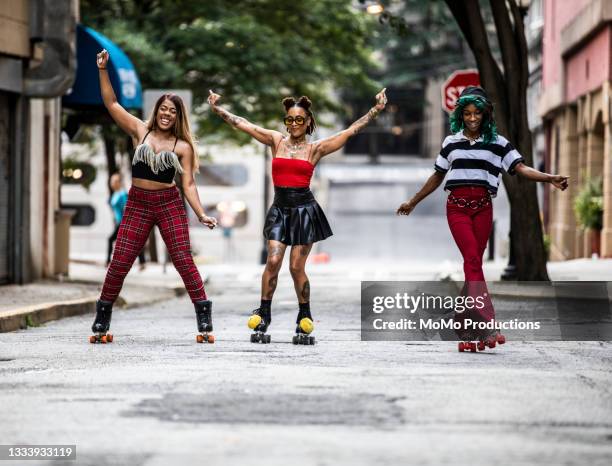 young women rollerskating in urban area - dreiviertel vorderansicht stock-fotos und bilder
