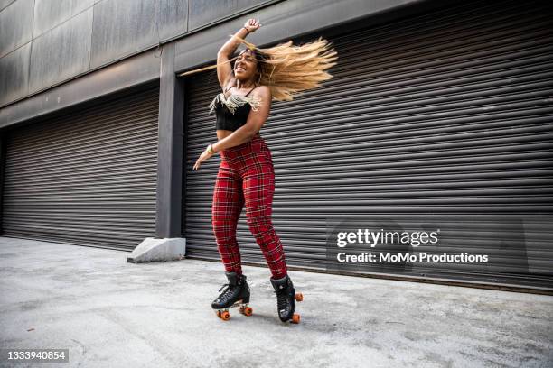 young woman rollerskating in urban area - red trousers stock-fotos und bilder