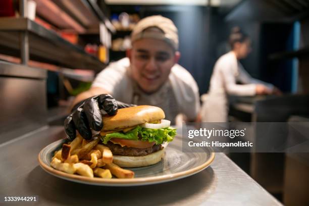 happy chef preparing burgers at a fast food restaurant - chef cuisine stockfoto's en -beelden