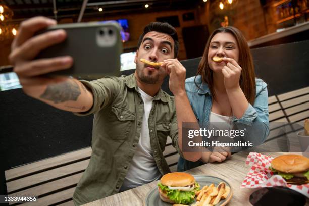 couple taking a funny selfie while eating at a restaurant - 2021 a funny thing 個照片及圖片檔