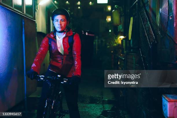 young man delivering food by bicycle - night delivery stock pictures, royalty-free photos & images
