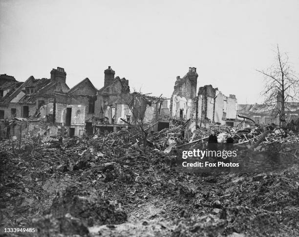 Two young schoolboys look down on the crater and damage from the explosion caused by V-2 Vergeltungswaffe 2 long-range liquid fueled guided ballistic...