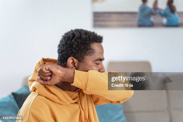adult man coughing or sneezing into elbow - elbow stockfoto's en -beelden