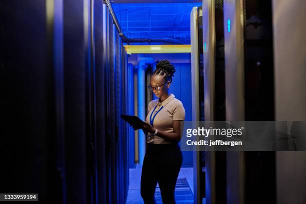 aufnahme einer jungen ingenieurin mit einem digitalen tablet bei der arbeit in einem serverraum - cloud computing stock-fotos und bilder
