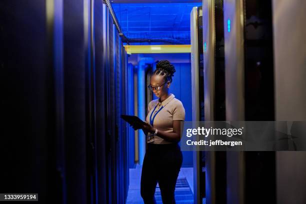 scatto di una giovane ingegnere donna che usa un tablet digitale mentre lavora in una sala server - it technician foto e immagini stock