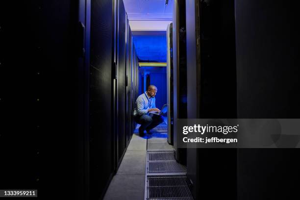 shot of a male engineer using a laptop while working in a server room - mainframe stock pictures, royalty-free photos & images