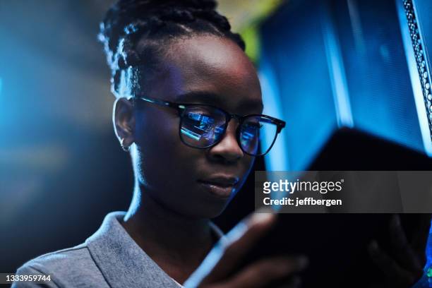 scatto di una giovane ingegnere donna che usa un tablet digitale mentre lavora in una sala server - server room women foto e immagini stock