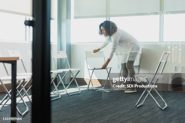 mid adult therapist prepares for group therapy - folding chair stock pictures, royalty-free photos & images