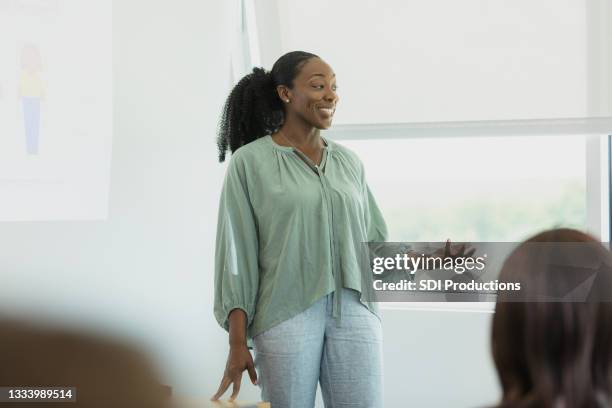 une femme adulte moyenne utilise des diapositives aériennes pendant la présentation - teaching photos et images de collection