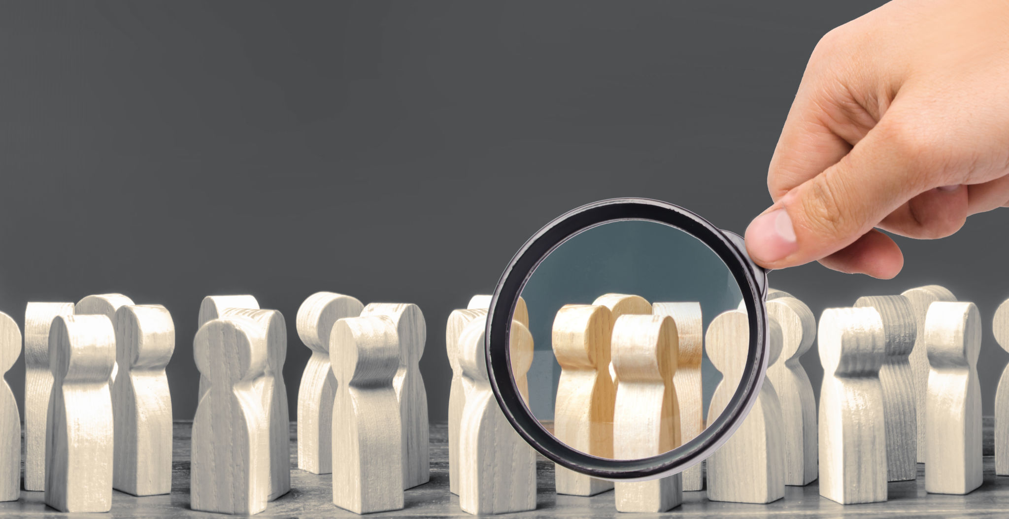 A magnifying glass looks at a crowd of wooden figures of people. society, demographic. group of citizens, rally, political movement or electorate. Customers and buyers, preferences of Population. A magnifying glass looks at a crowd of wooden figures of people. society, demographic. group of citizens, rally, political movement or electorate. Customers and buyers, preferences of Population.