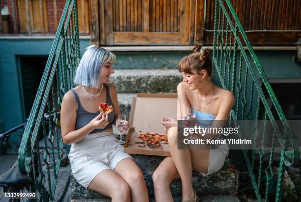 millennial girls eating pizza at stairs - friendship bracelet stock pictures, royalty-free photos & images