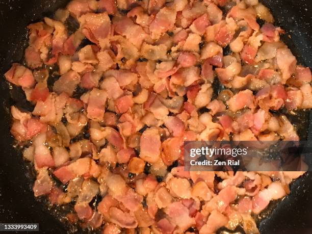 frying pieces of bacon on black cooking pan - saturated fat stock pictures, royalty-free photos & images