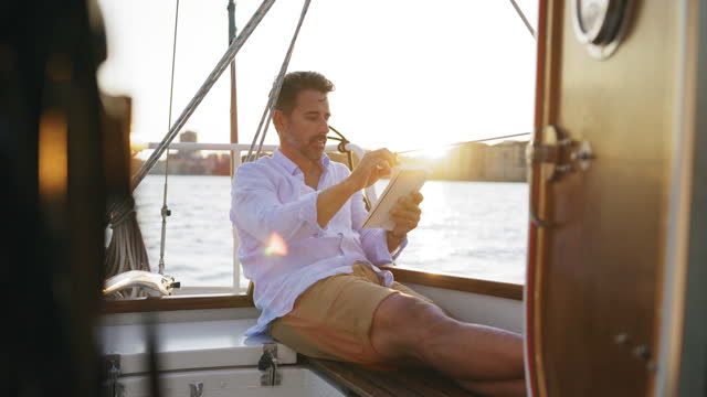 Man reading a book on his boat at sunset