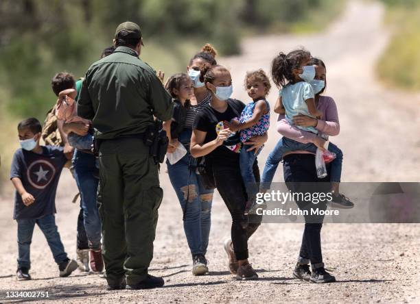 Border Patrol agent instructs immigrant families as they prepare to board transport to a processing center after crossing the U.S.-Mexico border on...