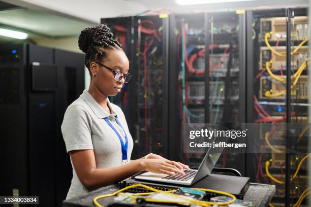 scatto di una giovane donna che usa un laptop in una sala server - server room women foto e immagini stock