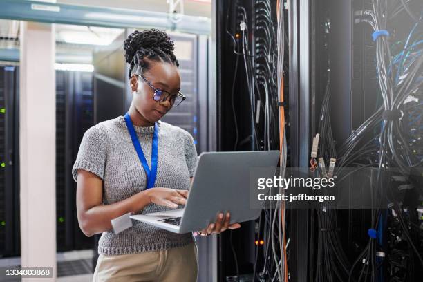 aufnahme einer jungen frau mit einem laptop in einem serverraum - female programmer stock-fotos und bilder