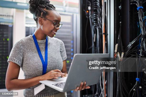 shot of a young woman using a laptop in a server room - technicus stockfoto's en -beelden