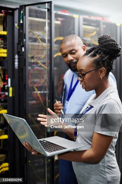 shot of two technicians working together on a laptop in a server room - online database stockfoto's en -beelden