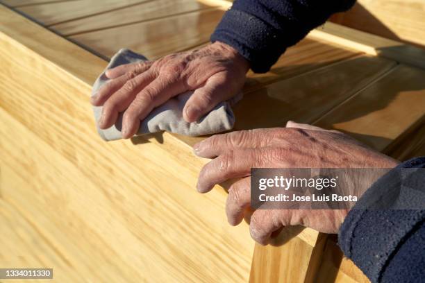 woodworker's hands polishing a wood board's surface - wooden surface finishes foto e immagini stock