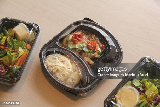 plastic containers of prepared food at kitchen table - meals on wheels stock pictures, royalty-free photos & images