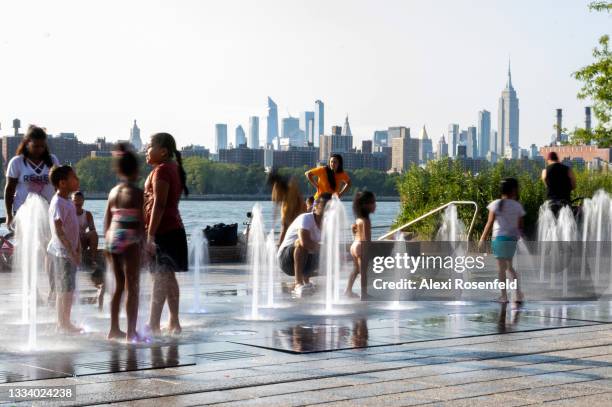 Children cool off in the Domino Park fountain as temperatures reached close to 100 degrees Fahrenheit with a view of the Manhattan skyline in the...