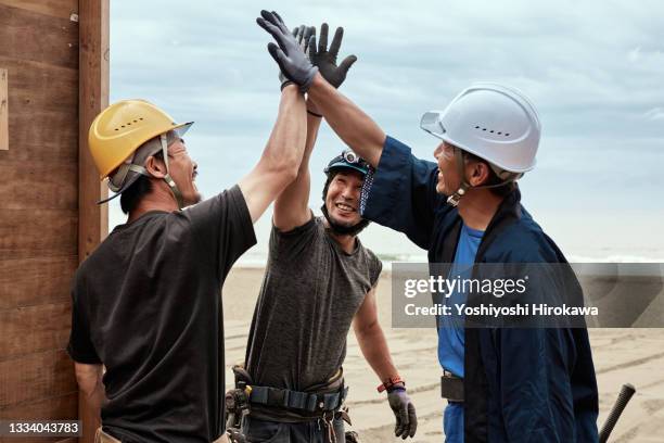 carpenters smile and give high fives - building partnership stock pictures, royalty-free photos & images