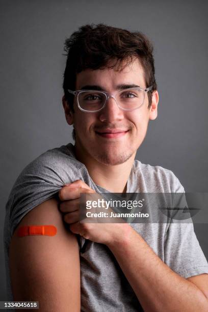 young man posing showing a band-aid in his arm - man studio shot stock pictures, royalty-free photos & images