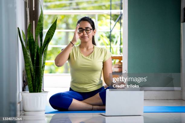 young woman in yoga pose using laptop at home - sports india stockfoto's en -beelden