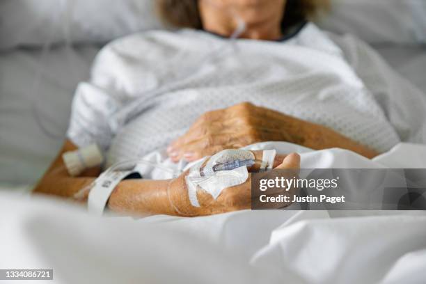 unrecognisable elderly female patient in hospital bed with pulse oximeter on finger - iv drip womans hand stock pictures, royalty-free photos & images