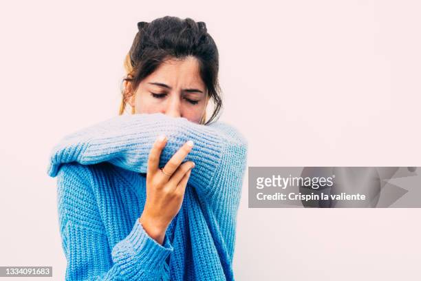 portrait of teenager girl dressed in blue sick - closeup of a hispanic woman sneezing foto e immagini stock