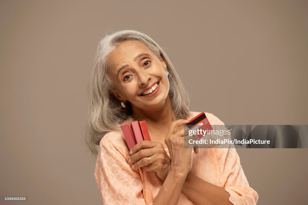 An old woman rejoicing with lipsticks and credit cards in her hand.