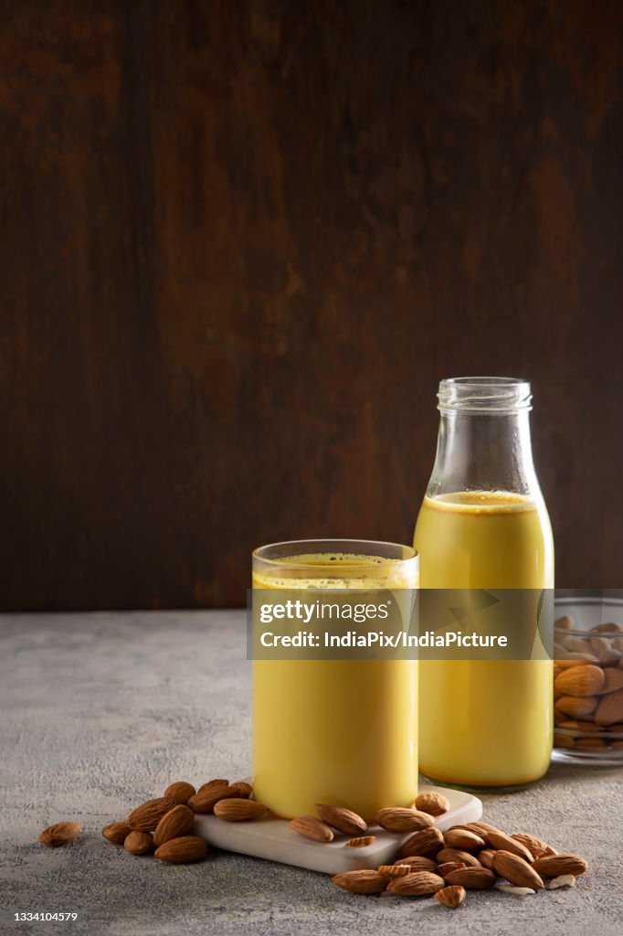 A glass and a bottle of healthy turmeric milk with almonds