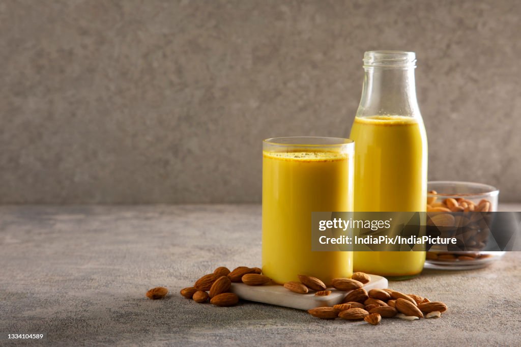 A glass and a bottle of healthy turmeric milk with almonds