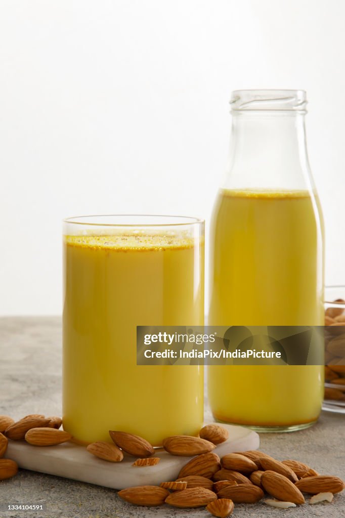A glass and a bottle of healthy turmeric milk with almonds