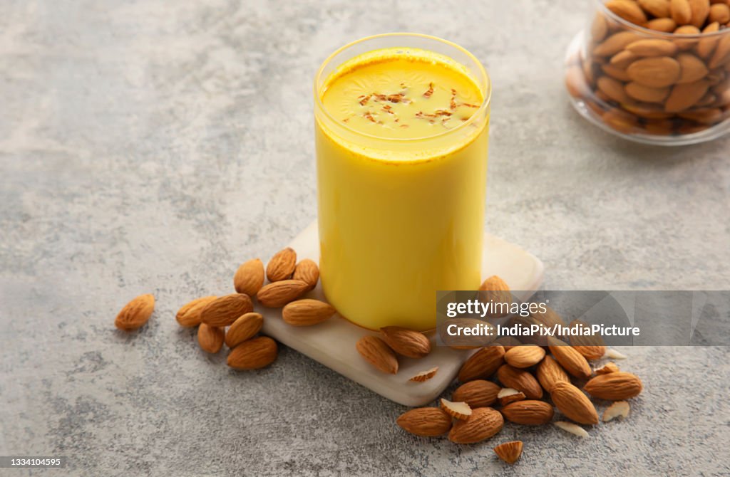 A glass and a bottle of healthy turmeric milk with almonds