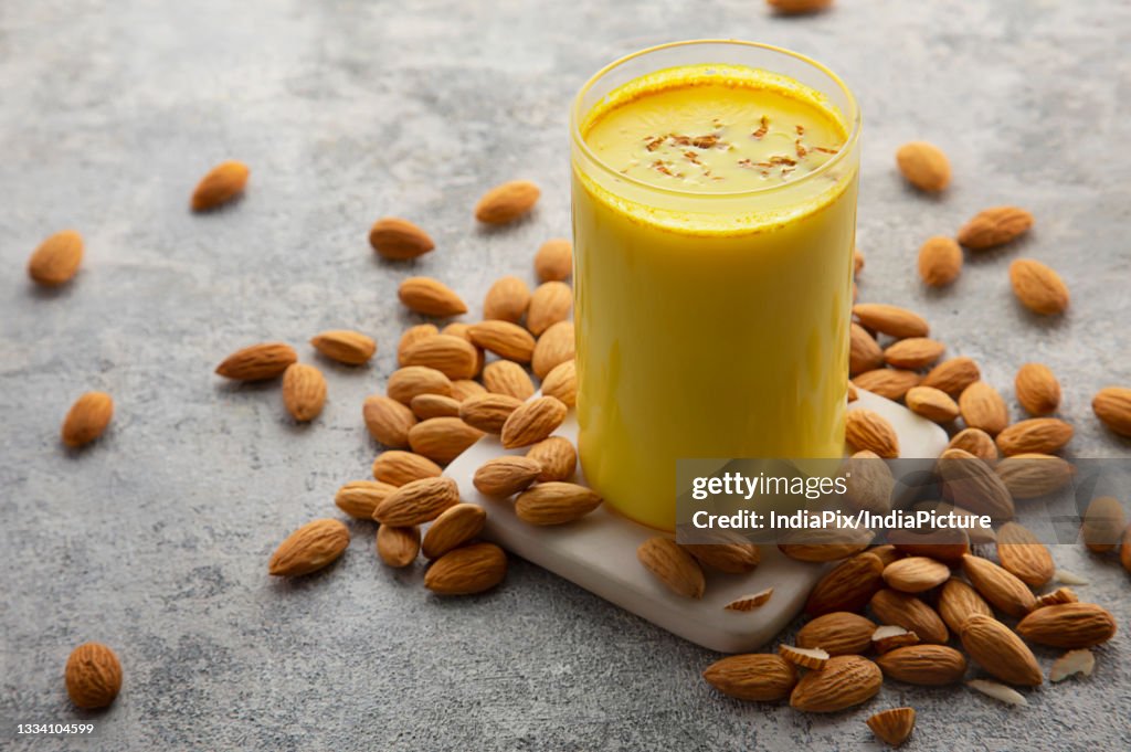A glass and a bottle of healthy turmeric milk with almonds