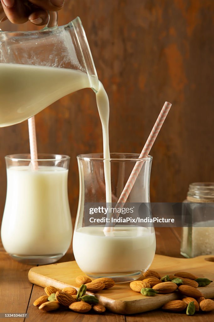 Butter Milk being poured in to a glass from a jug, with almonds