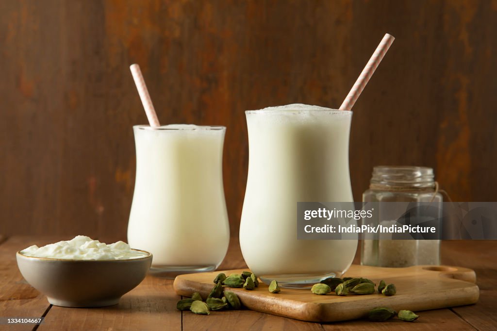 Butter milk in glasses On wooden Table with cardamom's