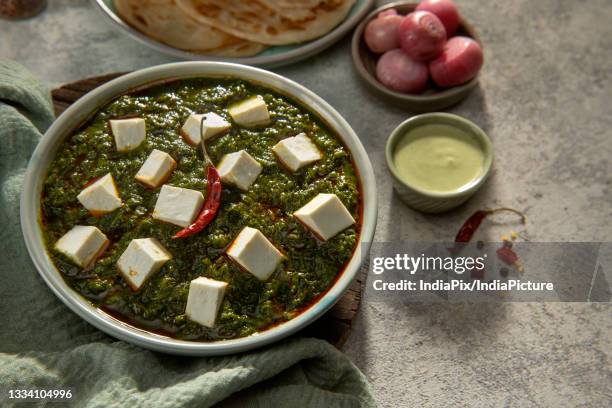 a garnished bowl of palak paneer served hot with chutney and paranthas - chili oil stock pictures, royalty-free photos & images
